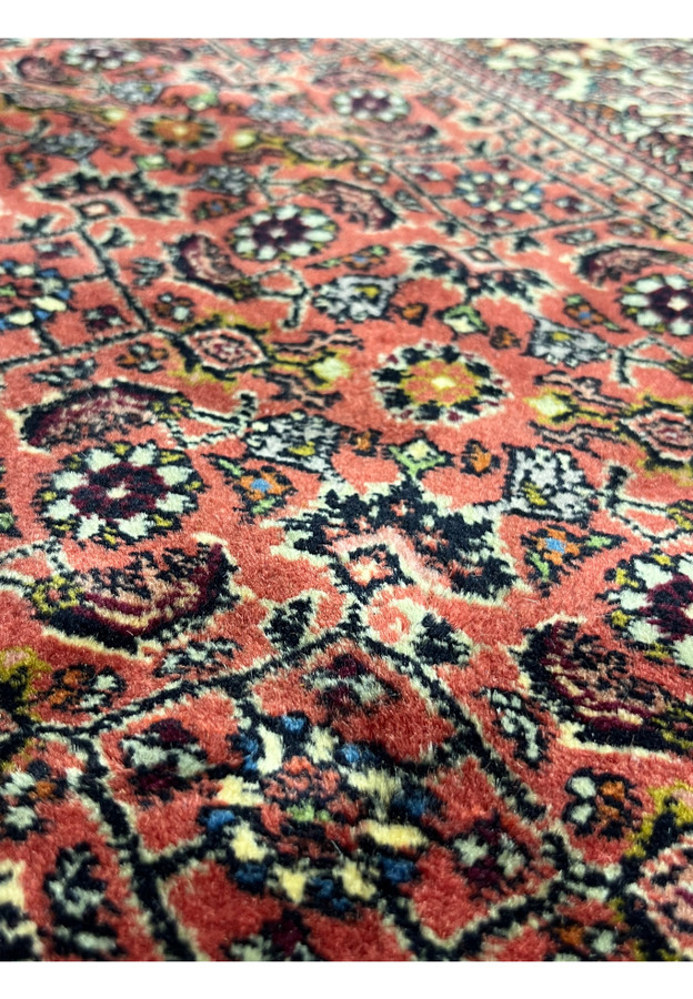 Color close-up of the rose red field with cream, navy, and gold Herati blossoms.