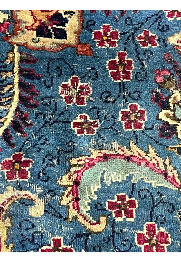 Worn down pile detail on blue field, honest view of heavily used Persian carpet