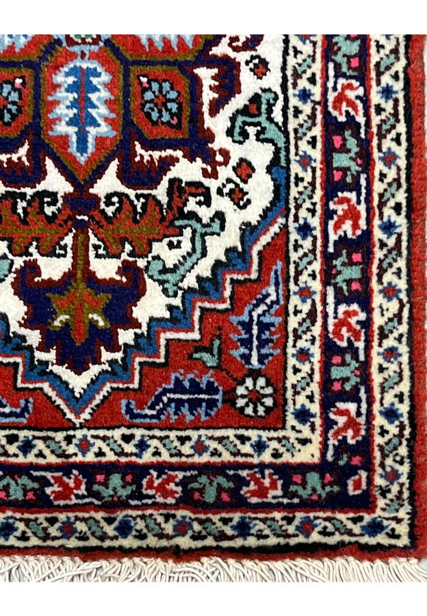 Border corner detail with red and mint flower vine and pink accents on small hand knotted rug