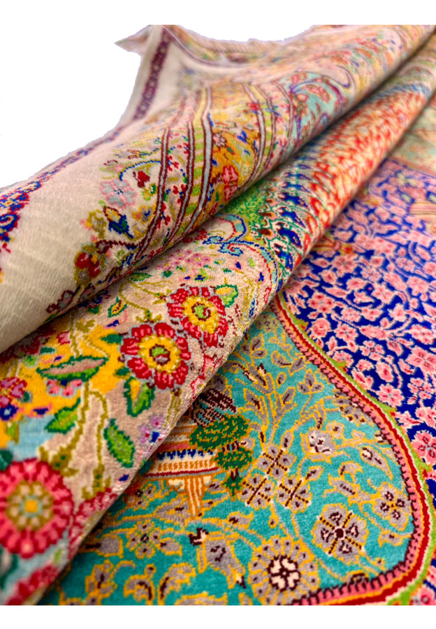 Rolled pure silk Qum showing liquid drape and vivid border detail in soft light
