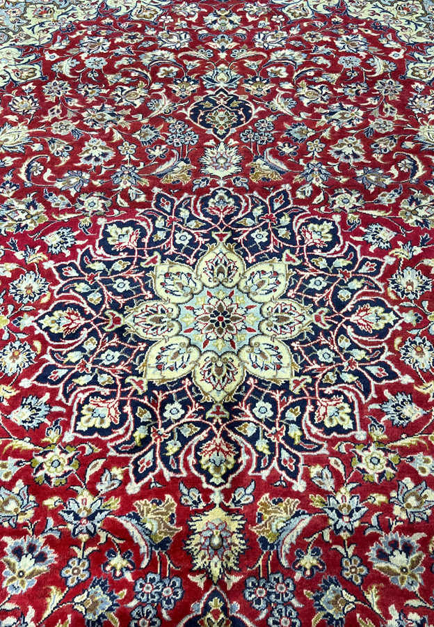 Navy cushioned medallion with pale ice blue core and cream cartouches on the red field