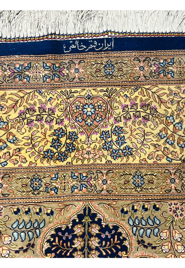 Woven cartouche reading Qum Khales, the pure Qum quality mark, on the navy end panel