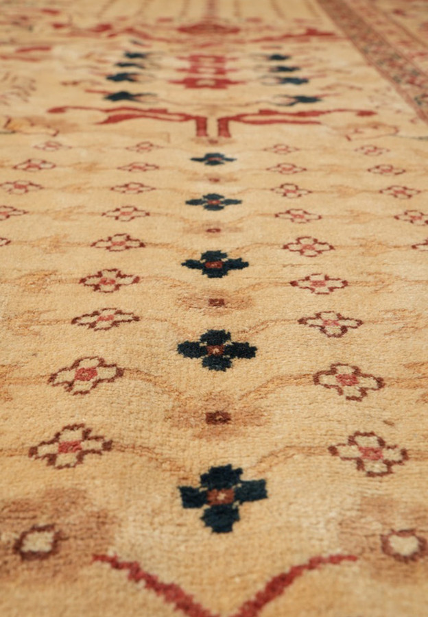 Close-up of hand-knotted Peshawar field showing all-over small rosette pattern in rust, navy, cream