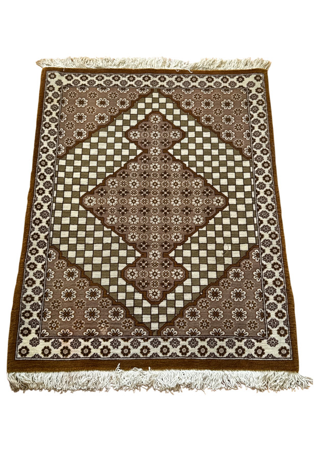 Small Persian Qum sample rug laid flat showing camel border and olive checkerboard pattern