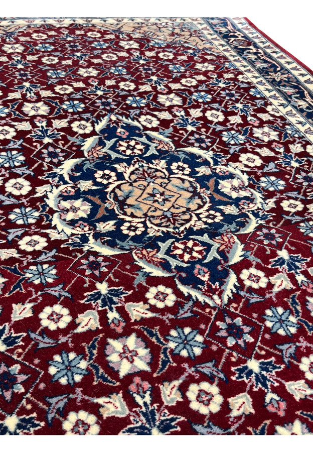 Color detail of a Persian Tabriz rug highlighting deep ruby field, navy blue medallion, ivory florals, soft beige accents, and balanced contrast