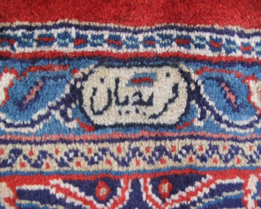 Close-up of the master weaver's signature etched elegantly into the border of the 10x13 Persian Sarough rug