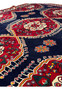 Angled view of a Persian Qashqai rug, emphasizing the depth of the dark blue field and the contrasting bright motifs throughout