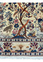 Detailed view of the lower section of a century-old Persian Kashan rug, focusing on the Tree of Life's base with animal interactions and intricate floral patterns