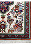 Corner section of a Persian Qum silk rug displaying the intricate border and fringe details against the floral patterns