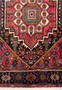 Angle view of the Persian Gholtogh rug showing the depth of the pile and the vibrant contrast between the red field and blue border.