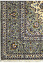 Corner section of a Persian Kashan rug, showing the detailed border meeting the rug’s cream field with floral patterns.