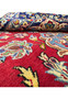 Close-up view of a 10 x 15'6" Persian Isfahan rug, highlighting its plush texture and vibrant design with intricate patterns in blue, yellow, and white on a rich red base.