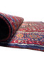 A rolled-up Persian Gholtogh rug, highlighting the patterns visible on the outer layer and giving a glimpse of its compact and sturdy weave.