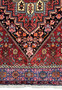 Detailed view of the upper part of a Persian Gholtogh rug, with a focus on the exquisite floral patterns and the ornate corners of the central diamond-shaped medallion