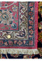 Close-up of the fringed edge of a Persian Isfahan rug, showing the tight weave and vibrant end border design.