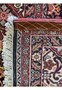 Edge detail of a Persian Bijar rug, showing the fringed end and the binding craftsmanship, alongside the geometric and floral border design