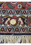 A close view of the Bijar rug's edge, featuring a coin for scale, showing the tight weave and elaborate border design