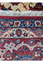 Edge view of a 10'7 x 14'7 Persian Isfahan Wool & Silk Rug, illustrating the border patterns and the rug's fringe.