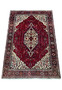 Full view of a Persian Qum Kork rug laid out on a flat surface, highlighting its detailed medallion and opulent red background