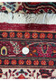 Close-up of the Persian Moud Rug's border, with a quarter placed for scale, showcasing the meticulous detail and rich heritage of Moud weaving technique