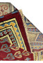 A close view of the corner of the rug, showcasing the precision of the patterns where the borders meet, with detailed motifs in blue, red, yellow, and cream.