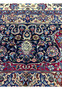 Close-up view of intricate floral and vine patterns on a Persian Mashad rug, highlighting the detailed craftsmanship with vibrant colors including deep red, blue, and ivory, showcasing traditional Persian design elements.