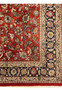 Top section of Sarough Persian rug showing transition from rust red floral field to navy floral border with ivory accents and dense Persian weave.”