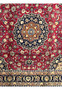 Midfield view of Mashad Rug featuring navy and gold medallion surrounded by red floral design