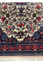 Lower edge of Persian Bijar Rug with floral border, fringes, and intricate roses on navy ground