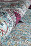 Rolled silk oriental rug with burgundy and sky-blue tones highlighting sheen and texture
