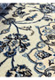 Close-up of Persian Nain 9LA Rug pattern showing navy and light-blue floral scrolls on ivory wool with silk accents.