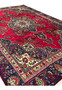 Angled view of 8'5" x 12'9" Persian Tabriz rug showing red field and navy corners