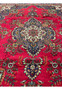 Close-up of detailed floral and vine patterns on red wool field of Persian Tabriz rug