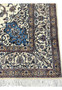 Detailed look at the border of the Persian Nain 4 LA Habibian rug featuring scrolling vines, beige and gold accents, and a thin crimson guard line.