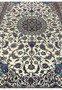 Top-angle view of a Persian Nain 4 LA Habibian rug showing luminous ivory field, navy floral motifs, and ornate royal blue corner designs.