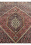 Detailed shot of the central medallion of Bijar Persian rug showing symmetrical floral motifs in ivory, rust, and navy with fine lattice outlines.