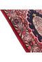 Angled edge view highlighting crimson pile, navy medallion edge, and ivory border with pink, brown, and blue vinework.
