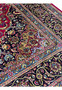Close-up of Persian Mashad rug border showing navy floral pattern with light blue guard border and red field details.