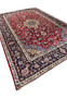 Angled view of 8'5 x 11'8 Persian Isfahan rug highlighting medallion, red field, and navy border.