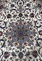 Close-up of the Persian Isfahan medallion featuring navy blue, burgundy, and pink floral details with silk highlights.