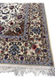 Border close-up with beige ground, navy floral motifs, and light-blue highlights from the Isfahan rug.