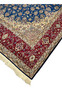 Edge and fringe view of the Persian Isfahan rug displaying precise knotting, red floral border, and navy outer edge.