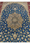 Close-up of the ornate Persian Isfahan medallion with cream, beige, and silk-accent detailing set against a blue floral field.