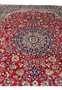 Detailed midfield view of Persian Isfahan rug showing dense floral motifs and crisp knotwork on ruby red field