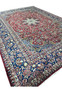 Angled view of the 9'9 x 14'5 Najafabad Persian rug highlighting the ruby field and strong navy border contrast.