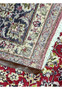 Backside of red Persian Isfahan rug showing tight knot structure, crisp pattern outlines, and traditional floral border layout.