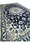 Angled view of royal navy Persian Nain rug showing wool texture and ivory medallion