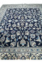 Midfield closeup of Persian Nain rug showing detailed floral vines, palmettes, and layered botanical motifs on navy background