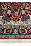 Lower border detail of Persian Isfahan rug showing navy floral guard borders, ivory accents, and hand knotted wool fringe