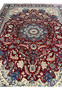 Top view of Persian Isfahan rug with symmetrical floral design, finely detailed medallion, and balanced red, ivory, and blue colors